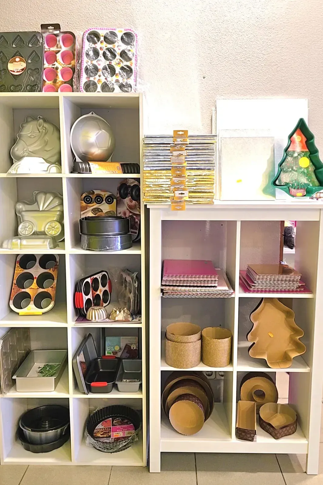 Dos estantes cúbicos blancos que muestran diversos elementos decorativos: cajas, adornos y decoración de temporada.