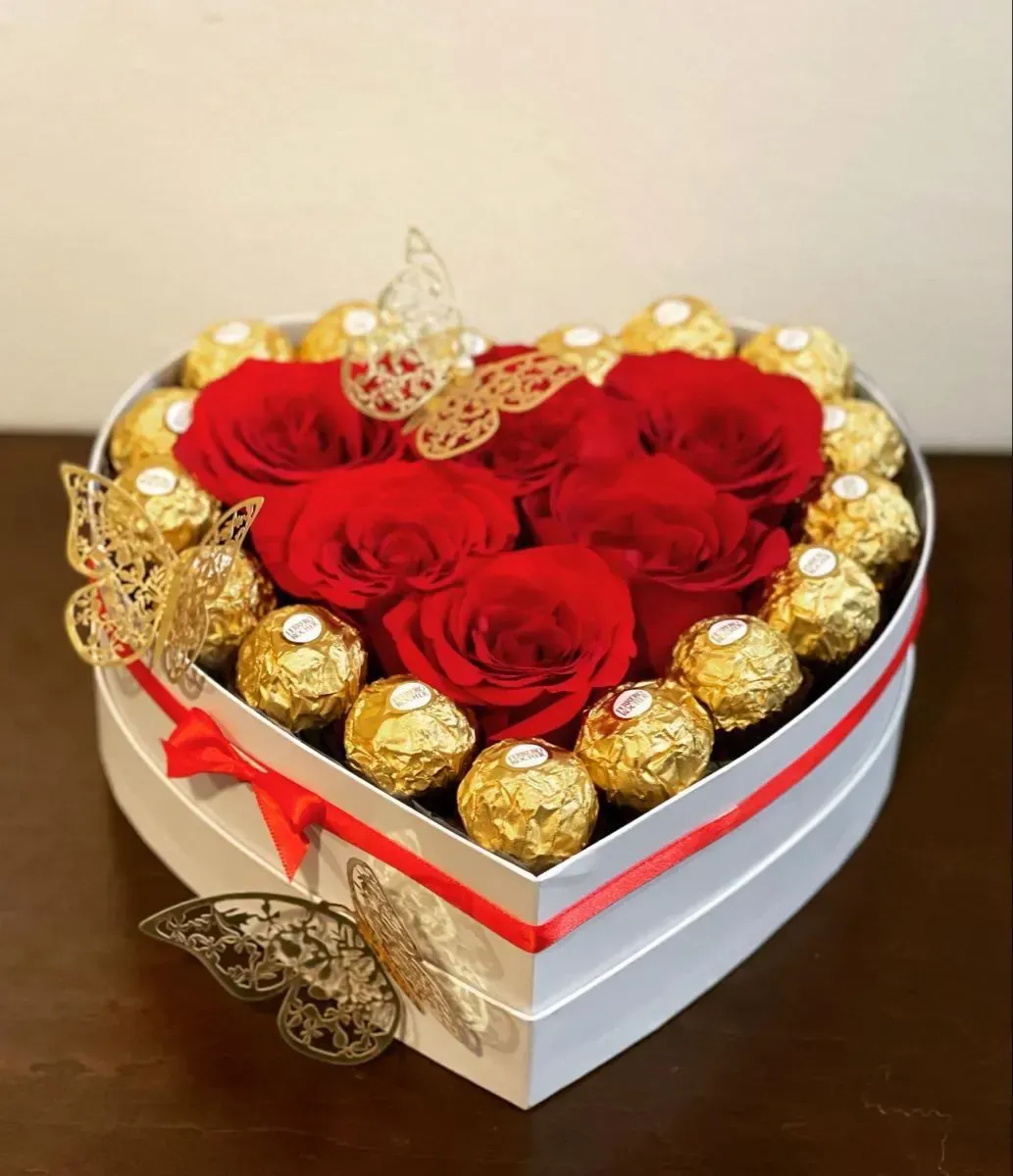 Caja en forma de corazón con rosas rojas y bombones de chocolate, decorada con mariposas.