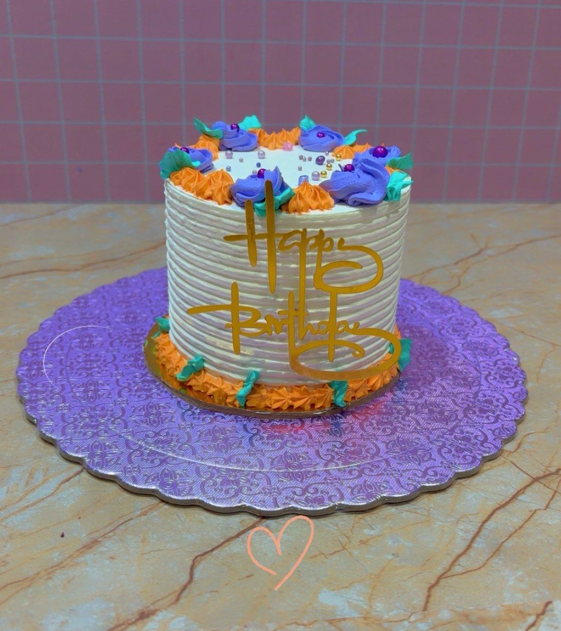 Un pequeño pastel de cumpleaños con glaseado blanco, texto dorado