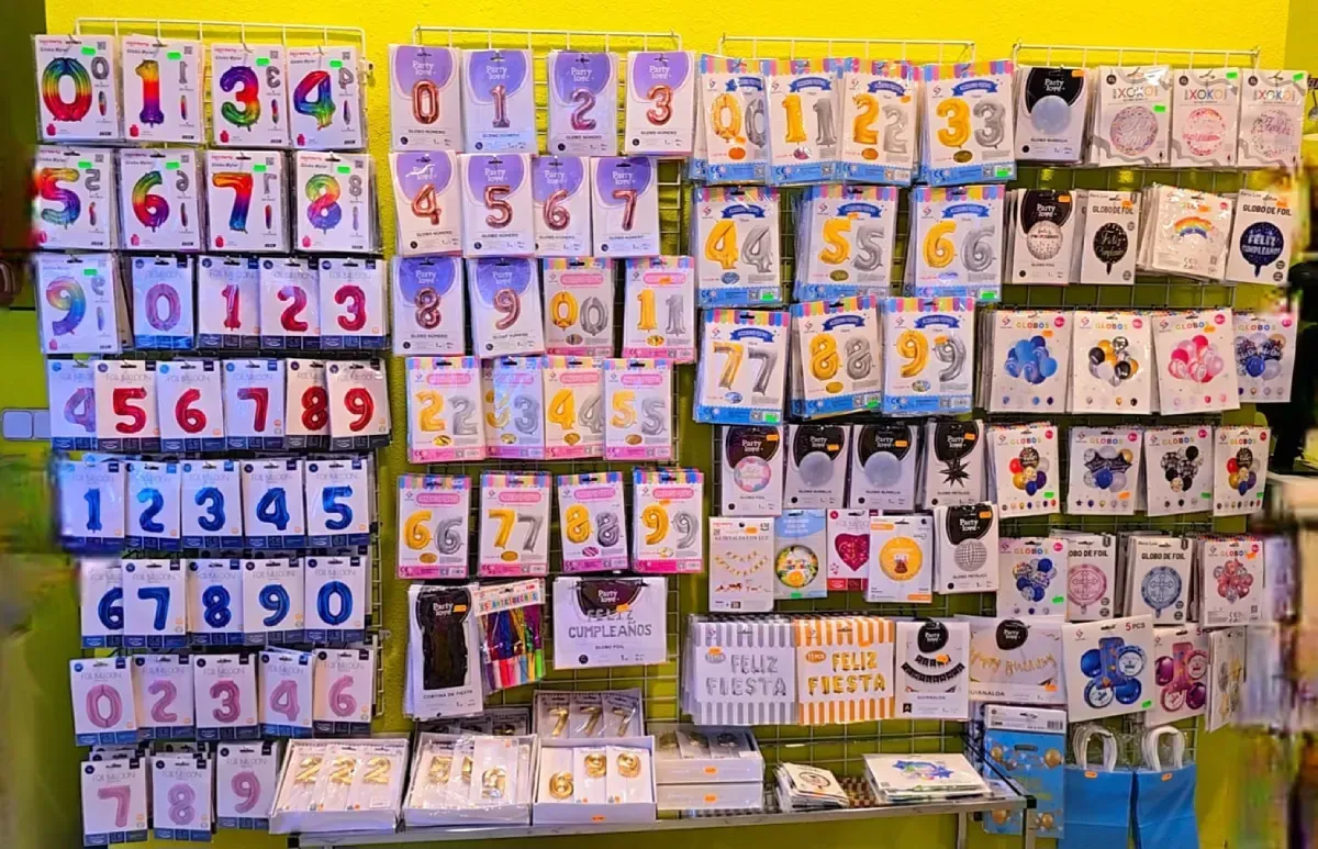 Exhibición de pared con globos con forma de números y decoraciones para fiestas en una tienda.