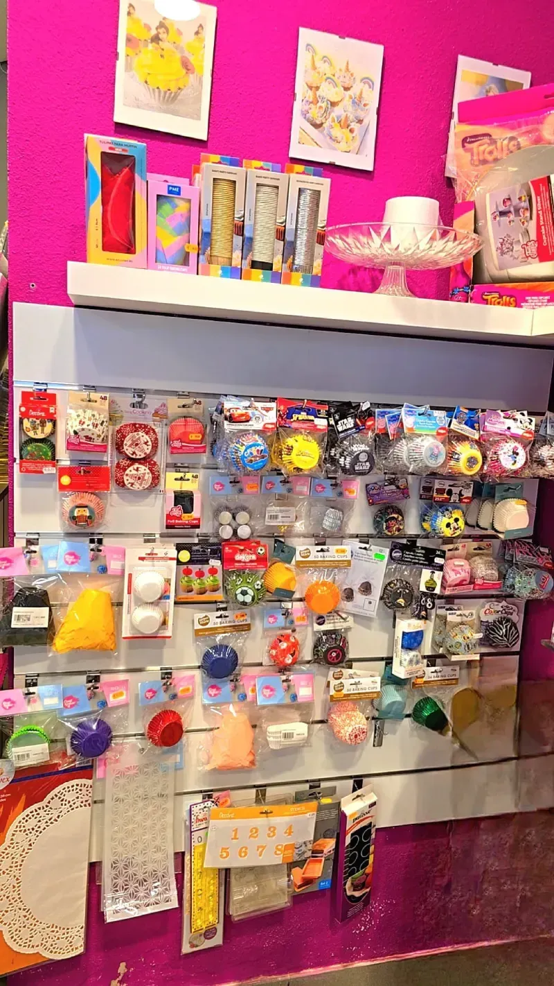 Exhibición de suministros para manualidades en una tienda contra una pared rosa;