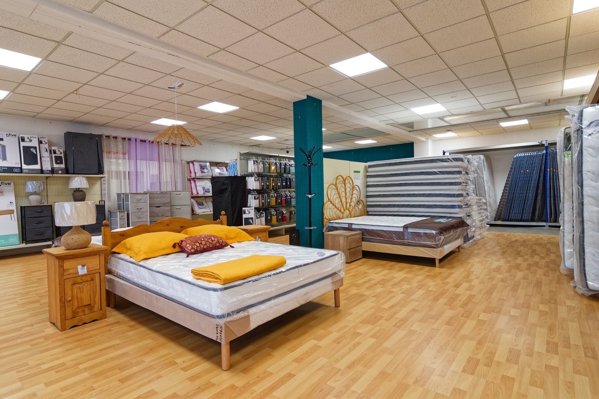 Un magasin de meubles de chambre à coucher avec des lits exposés, y compris un lit avec des oreillers jaunes.