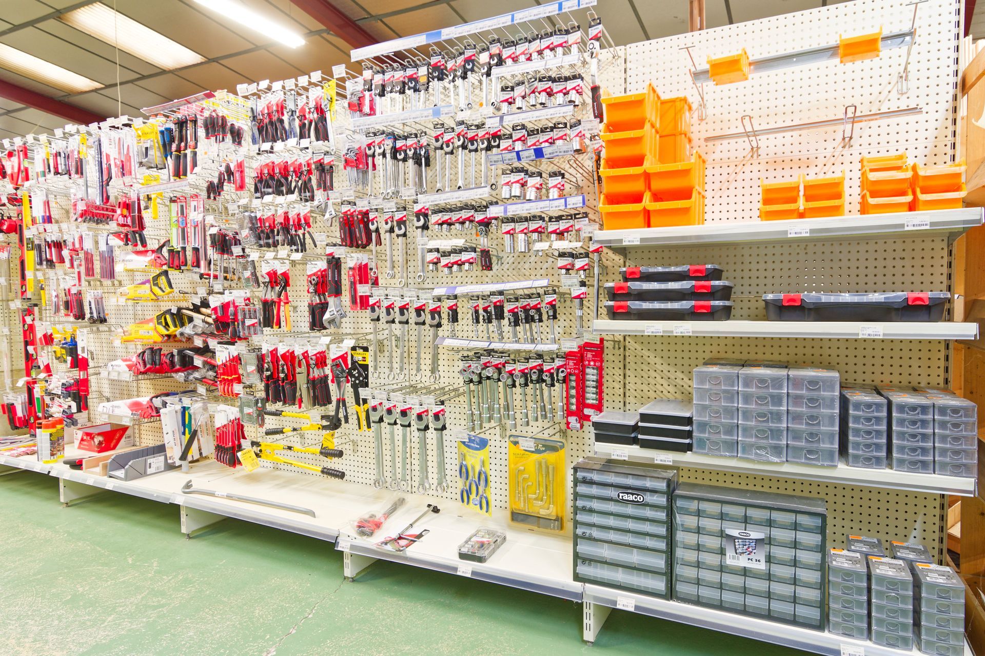 Outils exposés sur les étagères du magasin, avec des accents rouges et jaunes.
