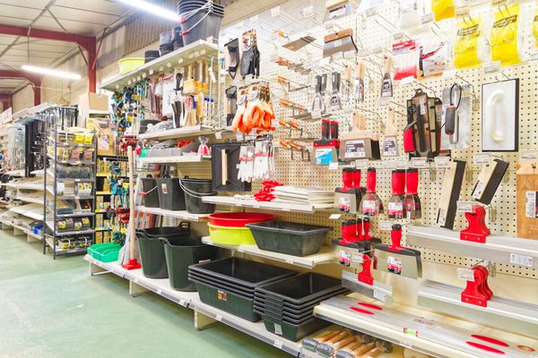 L'allée de la quincaillerie présente des outils, notamment des seaux, des gants et des truelles.