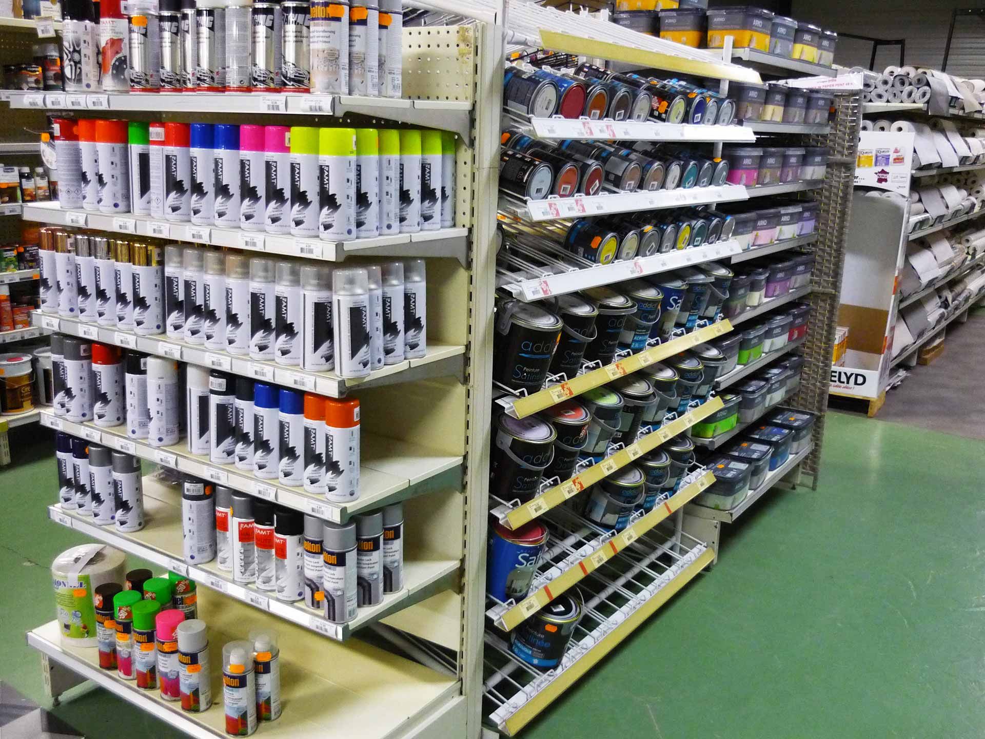 Des étagères dans un magasin remplies de diverses bombes de peinture de plusieurs couleurs.