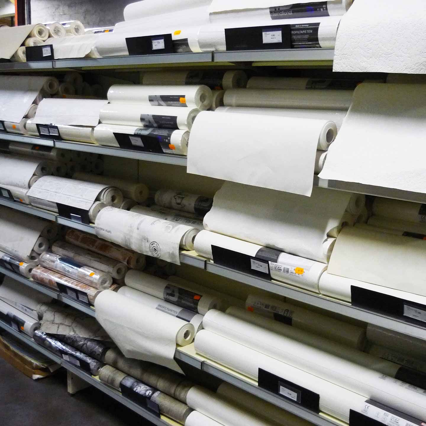 Des étagères remplies de rouleaux de papier peint blanc et à motifs dans un magasin.