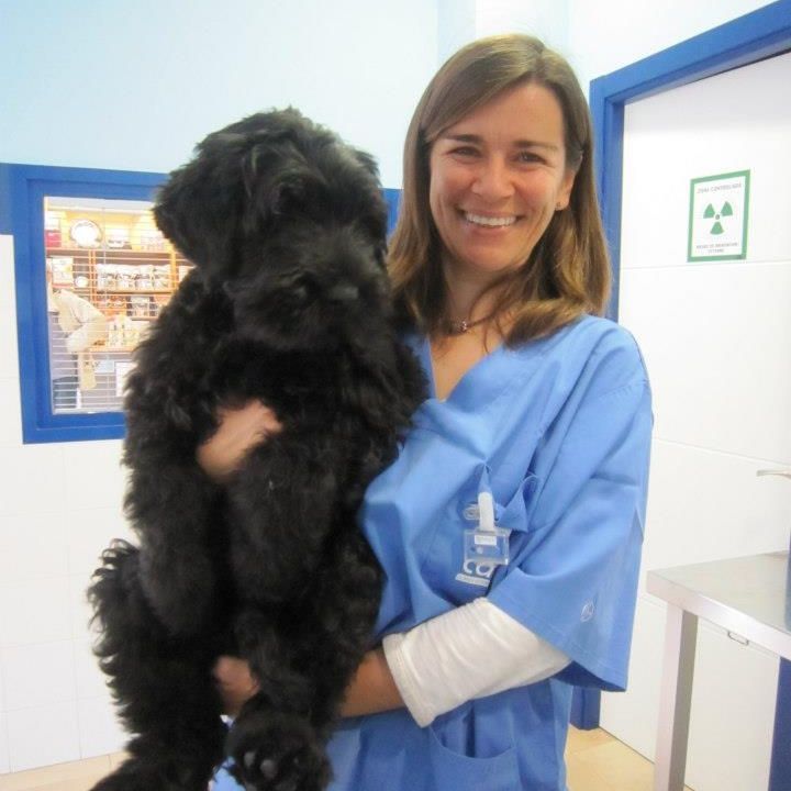 Una mujer con uniforme azul sostiene un perro negro.