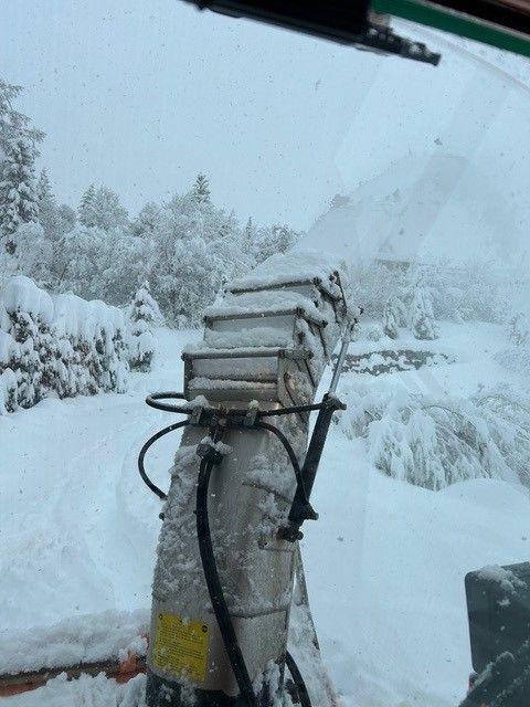 gros plan sur une machine crachant de la neige au milieu d'un paysage enneigé