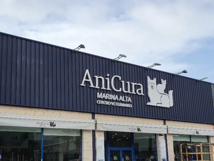 Clínica veterinaria AniCura Marina Alta con coches aparcados delante. Exterior azul oscuro, señalización