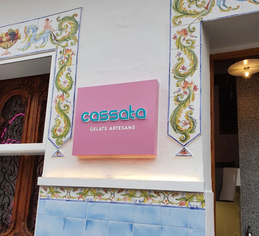 Letrero del restaurante Cassata rosa en un edificio con azulejos decorativos azules y blancos.