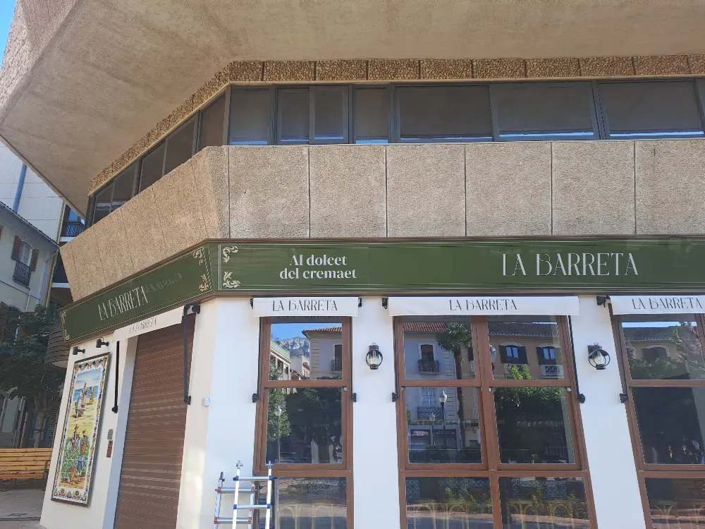 Exterior del restaurante “La Barreta” con fachada verde y blanca; cerrado, con persianas marrones.