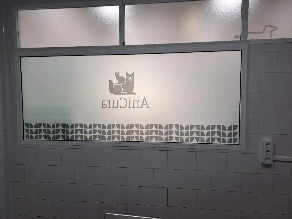 Ventana esmerilada con el logotipo “Anicats” y borde geométrico en una habitación embaldosada.