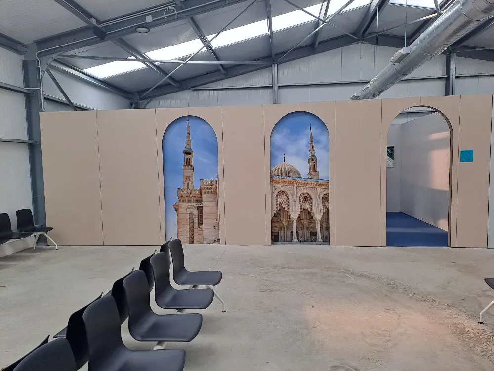 Una habitación abierta con una partición decorativa que presenta arcos con imágenes de mezquitas.