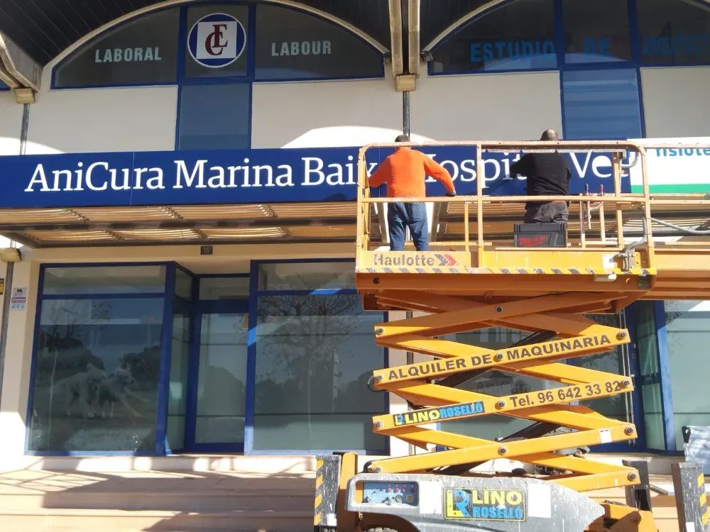 Obreros en un ascensor instalando un cartel que dice 
