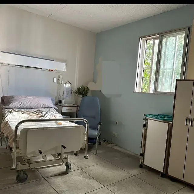 Una habitación de hospital con una cama y una silla.