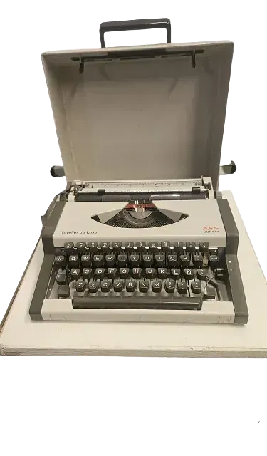 Una vieja máquina de escribir con la tapa abierta está sobre una mesa.