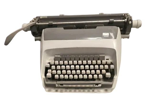 Una vieja máquina de escribir está sobre una superficie blanca.