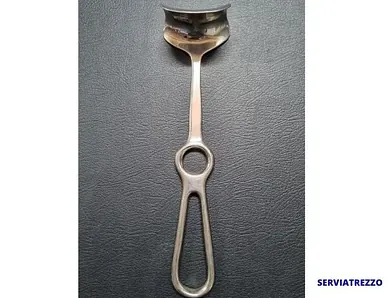 Una cuchara de plata con un agujero en el mango reposa sobre una superficie negra.