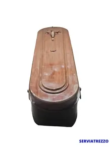 Un ataúd de madera está sobre una superficie blanca.