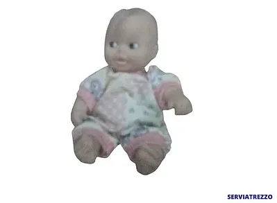 Una muñeca está sentada sobre una superficie blanca.