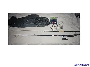 Una caña de pescar y un carrete están sobre una cama.