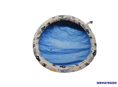 Una cama redonda para perro con una manta azul en su interior sobre un fondo blanco.