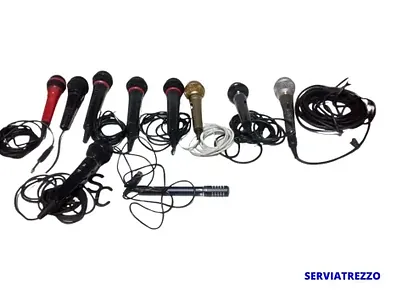 Un montón de micrófonos están colocados uno al lado del otro sobre un fondo blanco.