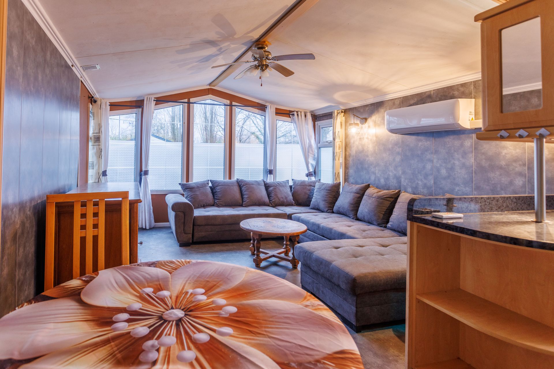 Intérieur d'un salon avec un canapé d'angle, une table basse et une grande fenêtre.