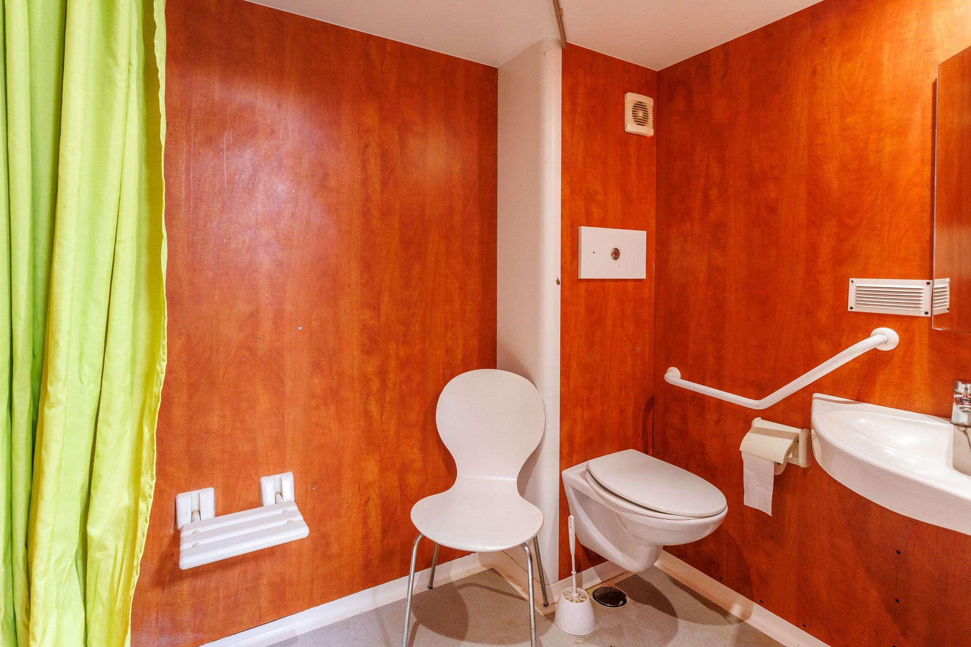 Salle de bain accessible avec dispositifs de sécurité, comprenant une barre d'appui, des toilettes et un lavabo.