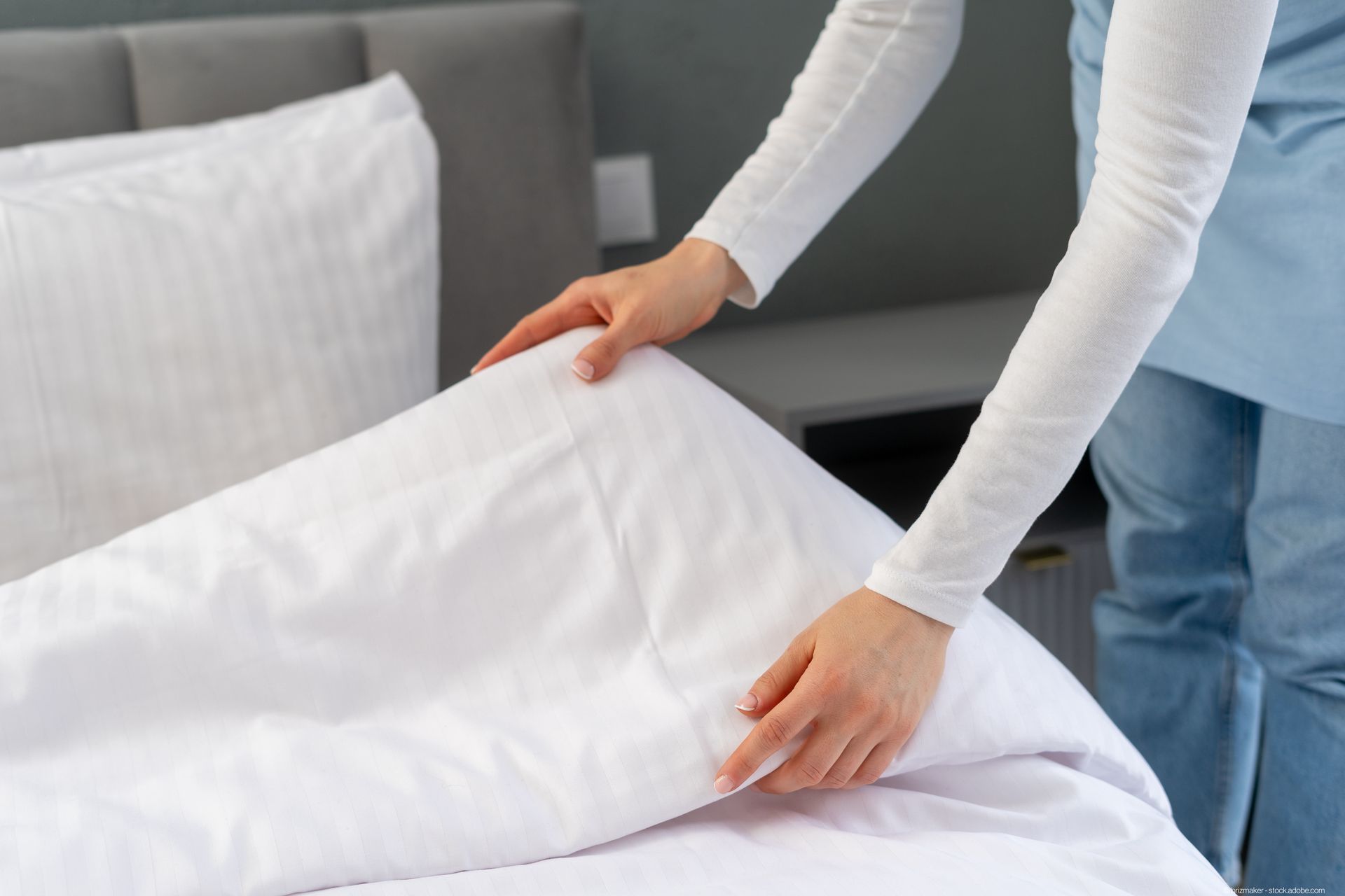 Frau macht das Bett im Hotelzimmer