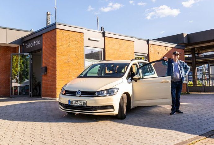 Ein Mann öffnet die Tür eines schwarzen Autos.