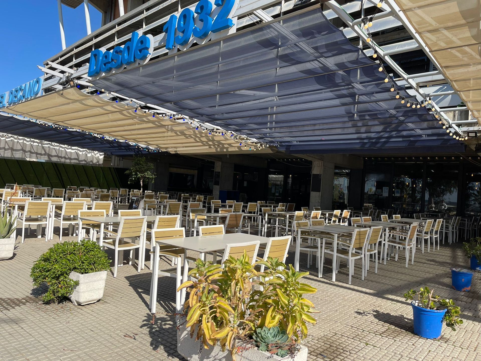 Un restaurante con mesas y sillas bajo un dosel que dice desde 1932