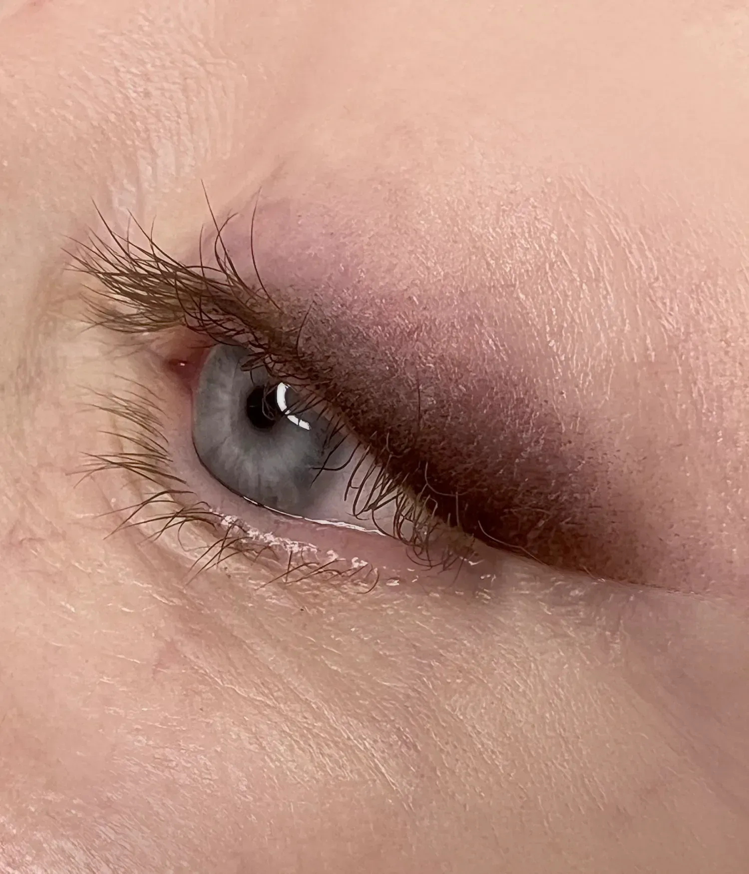 Primer plano del ojo con delineador negro y rímel, iris marrón y ceja definida.