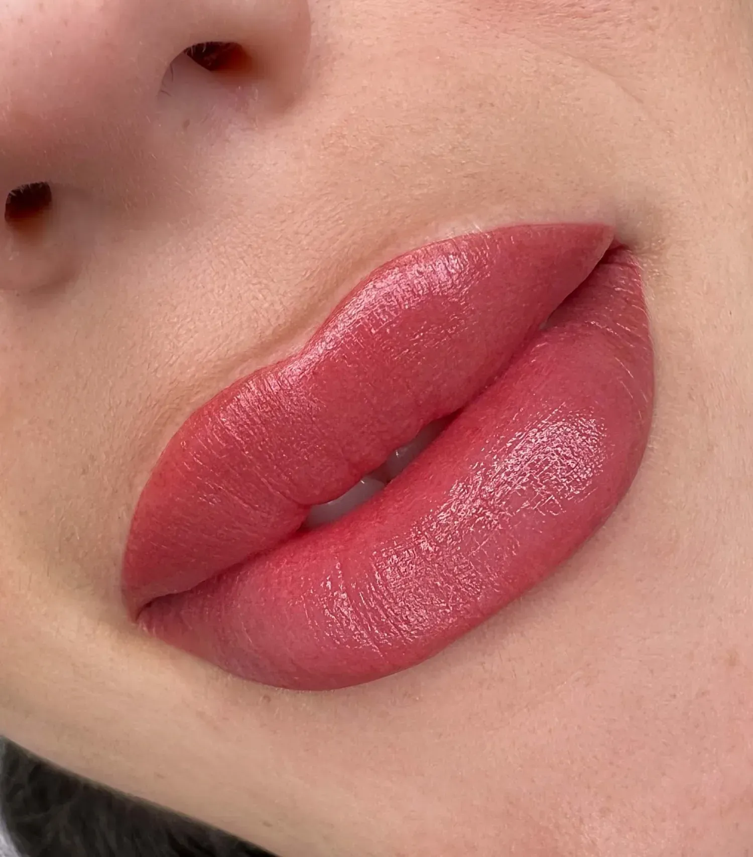 Primer plano de unos labios carnosos y rosados con un brillo suti