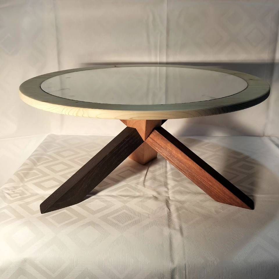 Une table ronde avec un plateau en verre et des pieds en bois. Photo D'équerre et d'aplomb