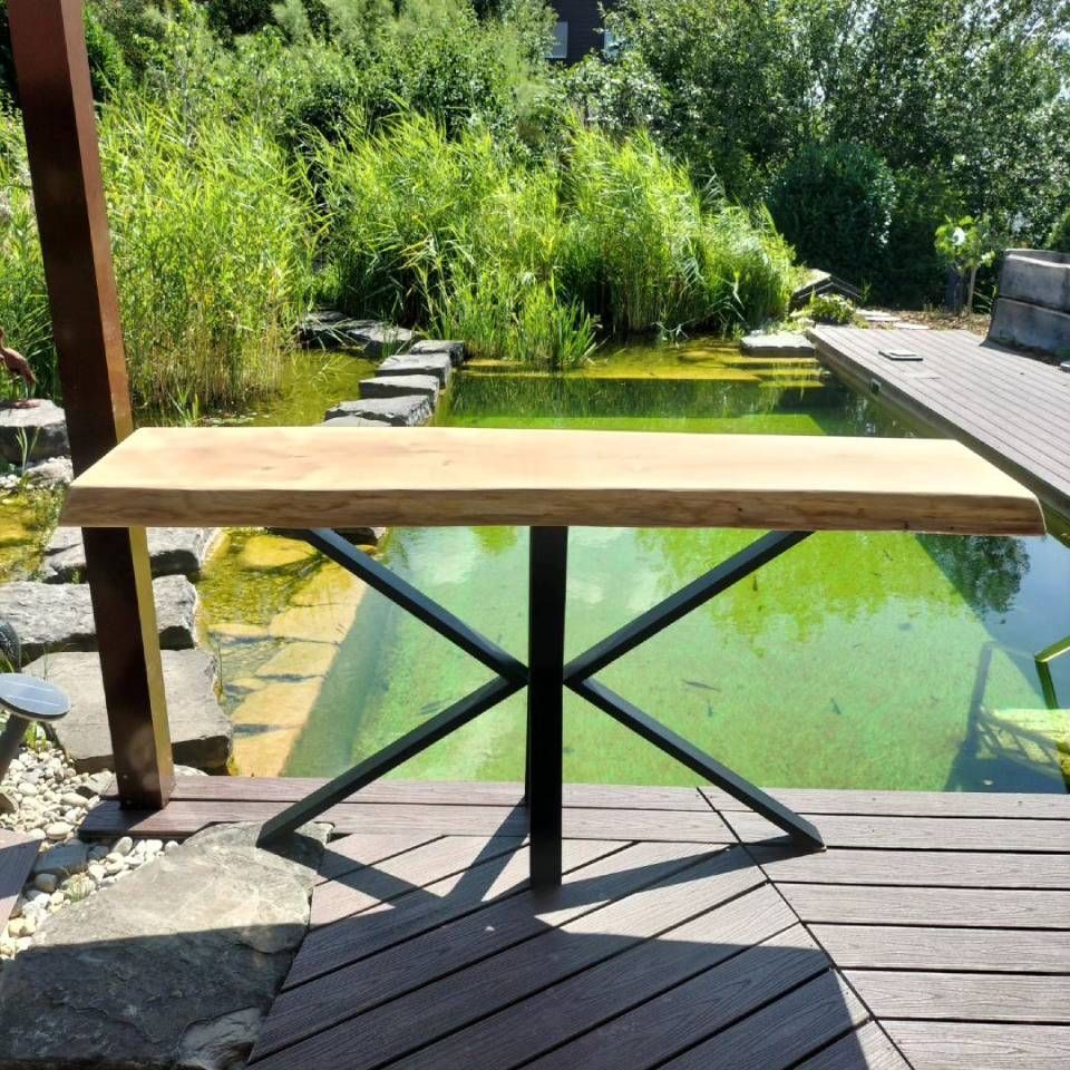 Une table en bois est posée sur une terrasse surplombant un étang. Photo D'équerre et d'aplomb