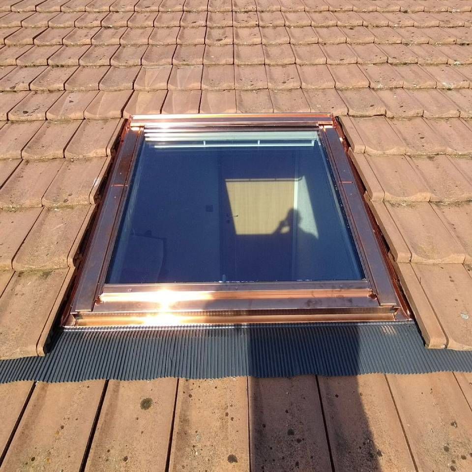 Une lucarne sur un toit en tuiles avec un cadre en cuivre. Photo D'équerre et d'aplomb