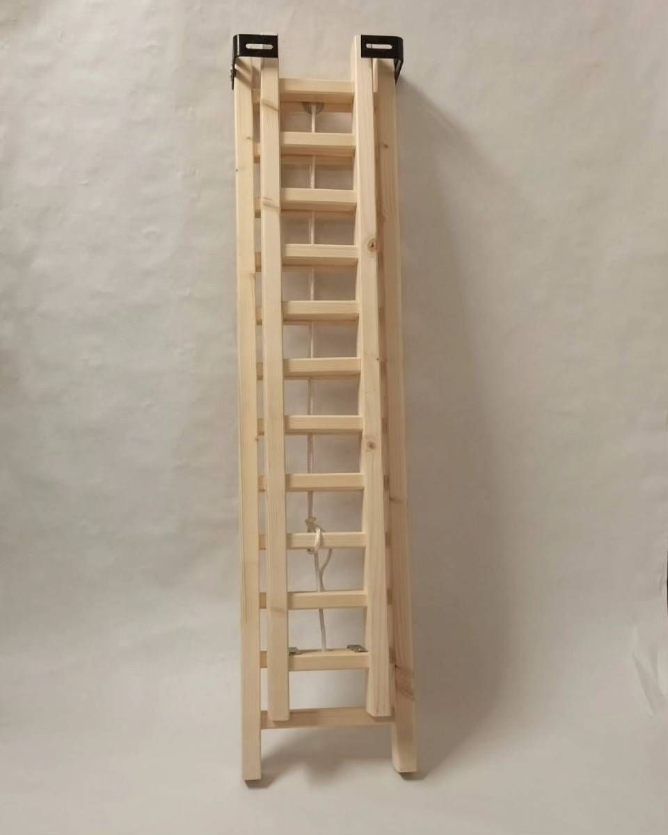 Une échelle en bois est appuyée contre un mur blanc. Photo D'équerre et d'aplomb