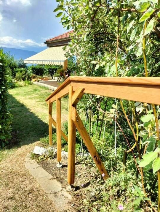 Une balustrade en bois dans un jardin avec une maison en arrière-plan. Photo D'équerre et d'aplomb