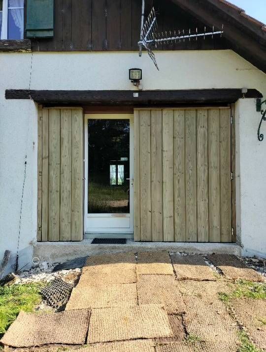 Une maison blanche avec une porte et des volets en bois. Photo D'équerre et d'aplomb