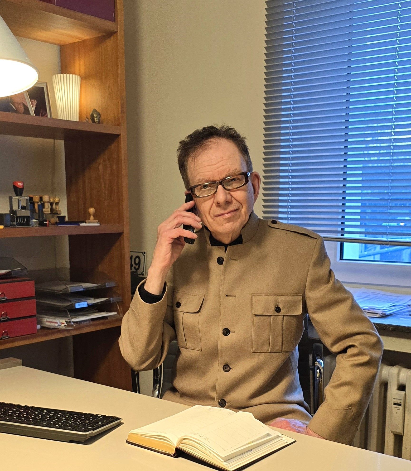 Eine Person im Anzug unterschreibt Dokumente an einem Tisch, im Vordergrund eine goldene Waage der Gerechtigkeit.