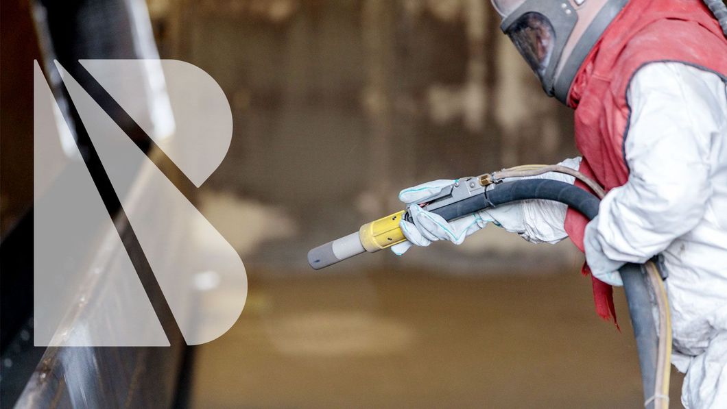 Ein Mann mit Helm und Handschuhen sandstrahlt