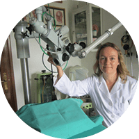 Mujer con bata de laboratorio junto a un microscopio. Campo quirúrgico verde. Configuración de la sala.