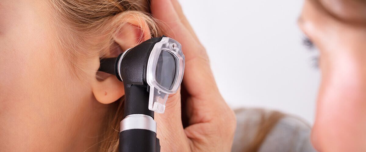 Un profesional médico que utiliza un otoscopio para examinar el oído de una persona.