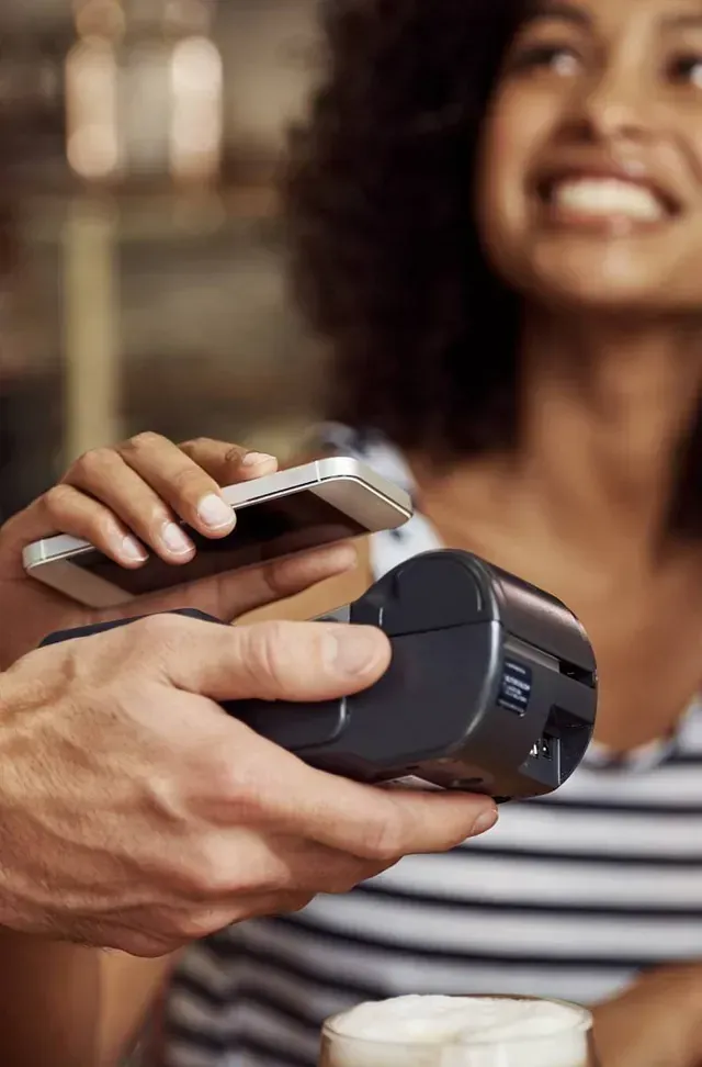 Una mujer está pagando una taza de café con su teléfono.