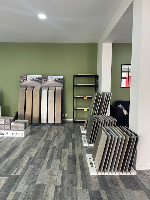 Intérieur d'une salle d'exposition de carrelage avec des présentoirs de sols et de murs sur fond de murs verts et blancs.