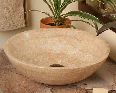 Meuble de salle de bains avec un robinet chromé et vasque noire texturée. Fond carrelé beige.