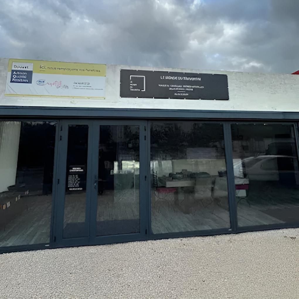 Extérieur d'un bâtiment avec des portes vitrées et des enseignes commerciales.