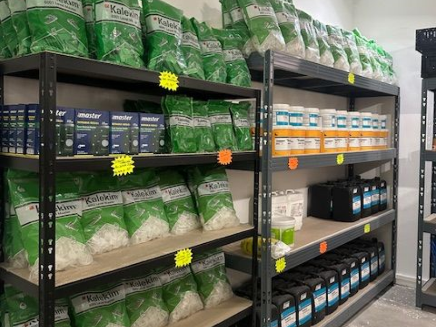 Outils et carreaux blancs sur une surface grise, notamment un niveau rouge, une pince à carreaux et des croisillons.