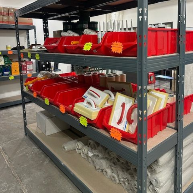 Pose de carreaux noirs avec des croisillons jaunes, outils et gants à proximité.